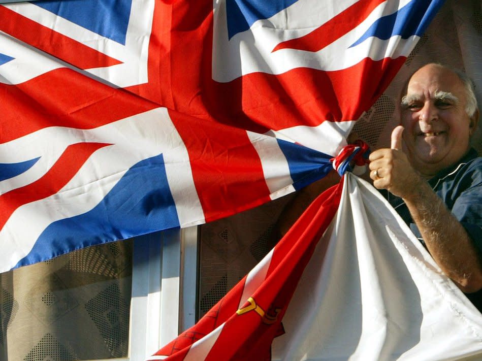 A Gibraltarian gives the thumbs up from his balcony which is adorned with Gibraltarian and Union flags in the British colony of Gibraltar November 6, 2002. [Gibraltar chief minister Peter Caruana predicts the colony's people will overwhelmingly reject the idea of Spain and Britain sharing sovereignty over the rock in a referendum scheduled for November 7