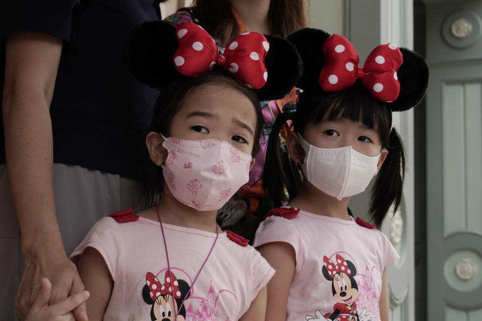 Young visitors wearing face masks look at the iconic cartoon characters Goofy and Pluto at the Hong Kong Disneyland, Friday, Sept. 25, 2020. Hong Kong Disneyland reopened its doors to visitors after closed temporarily due to the coronavirus outbreak. (AP Photo/Kin Cheung)