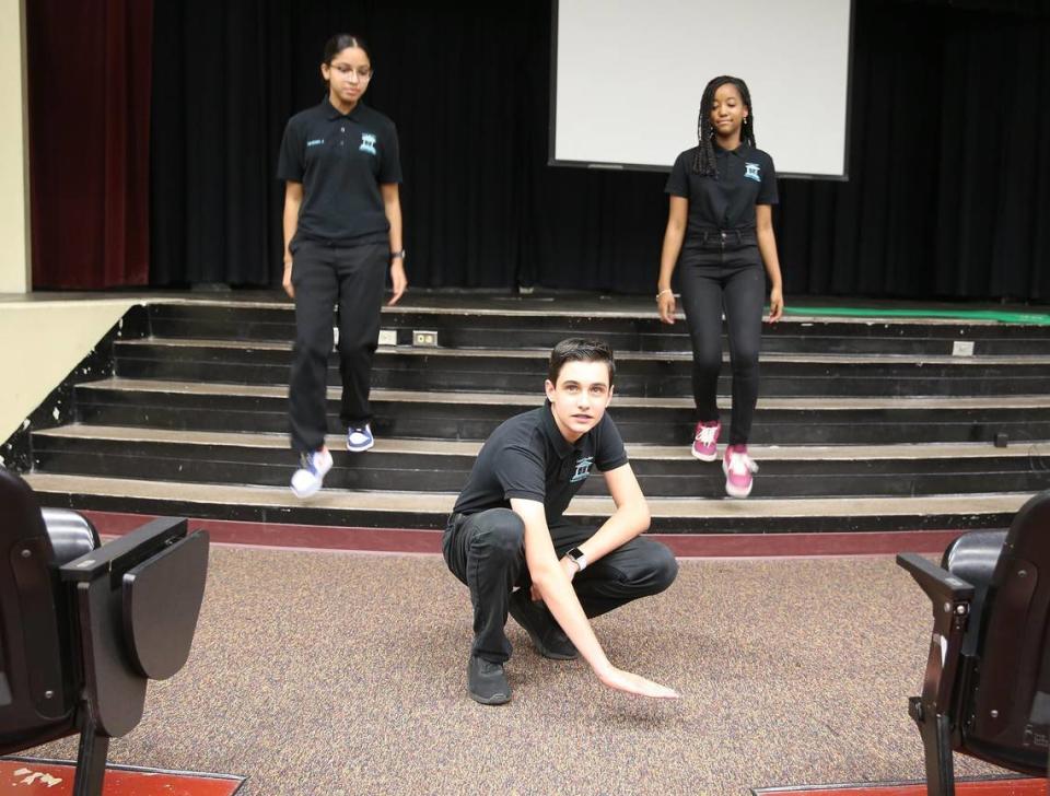 Maurits Acosta shows the level of the water in the auditorium after a storm as Jocelyn Hernandez and Gabriella Vega descend the stairs on June 9, 2021. Miami Lakes Middle School students have proposed flood prevention legislation to the town council after Tropical Storm Eta flooded parts of the west Miami-Dade town, including their school auditorium.