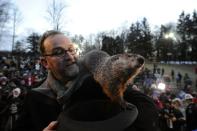 PUNXSUTAWNEY, PA - FEBRUARY 2: Groundhog handler Ben Hughes watches Punxsutawney Phil after he did not see his shadow predicting an early spring during the 125th annual Groundhog Day festivities on February 2, 2011 in Punxsutawney, Pennsylvania. Groundhog Day is a popular tradition in the United States and Canada. A smaller than usual crowd this year of less than 15,000 people spent a night of revelry awaiting the sunrise and the groundhog's exit from his winter den. If Punxsutawney Phil sees his shadow he regards it as an omen of six more weeks of bad weather and returns to his den. Early spring arrives if he does not see his shadow causing Phil to remain above ground. (Photo by Jeff Swensen/Getty Images)