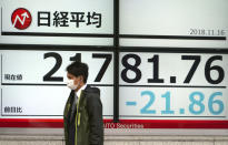 A man walks past an electronic stock board showing Japan's Nikkei 225 index at a securities firm in Tokyo Friday, Nov. 16, 2018. Shares were mixed in early trading in Asia on Friday on revived concerns over the prospects for a breakthrough in trade tensions between the U.S. and China.(AP Photo/Eugene Hoshiko)