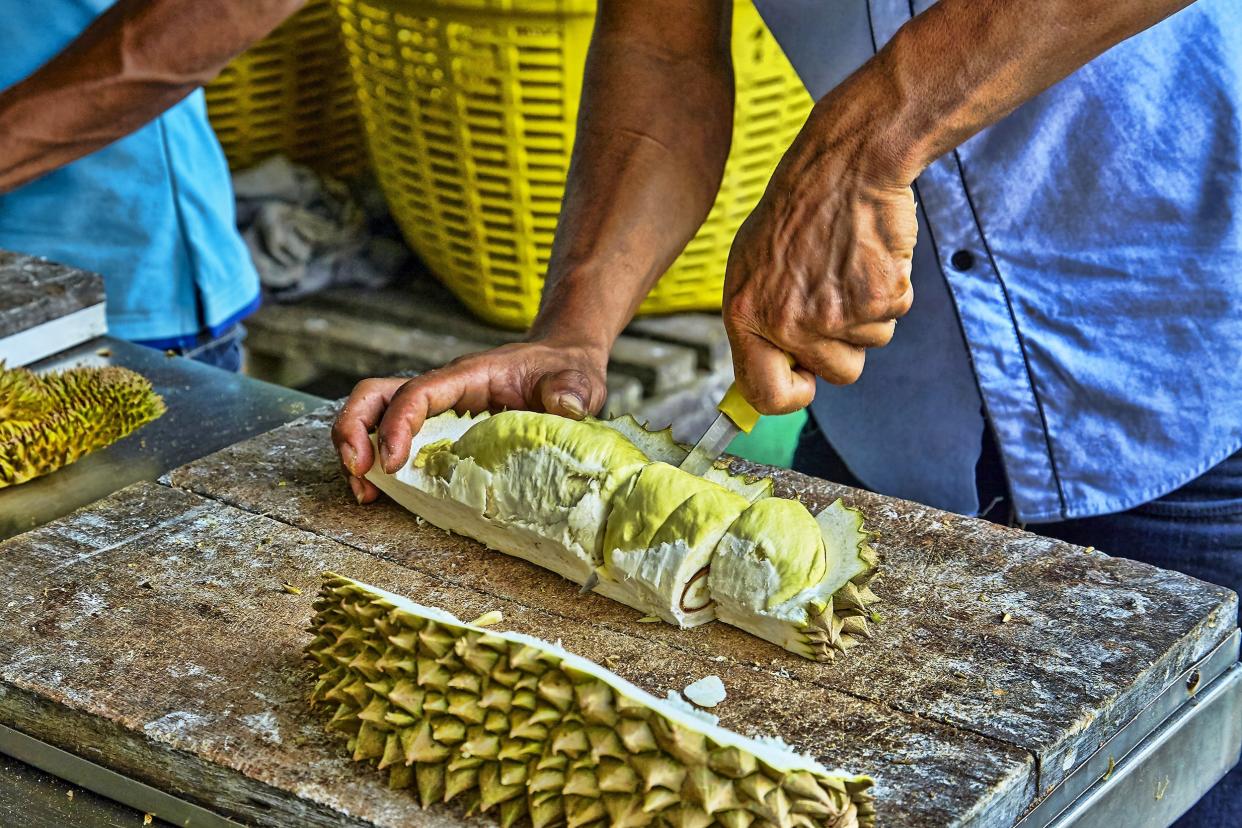 man cleans durian in Thailand market