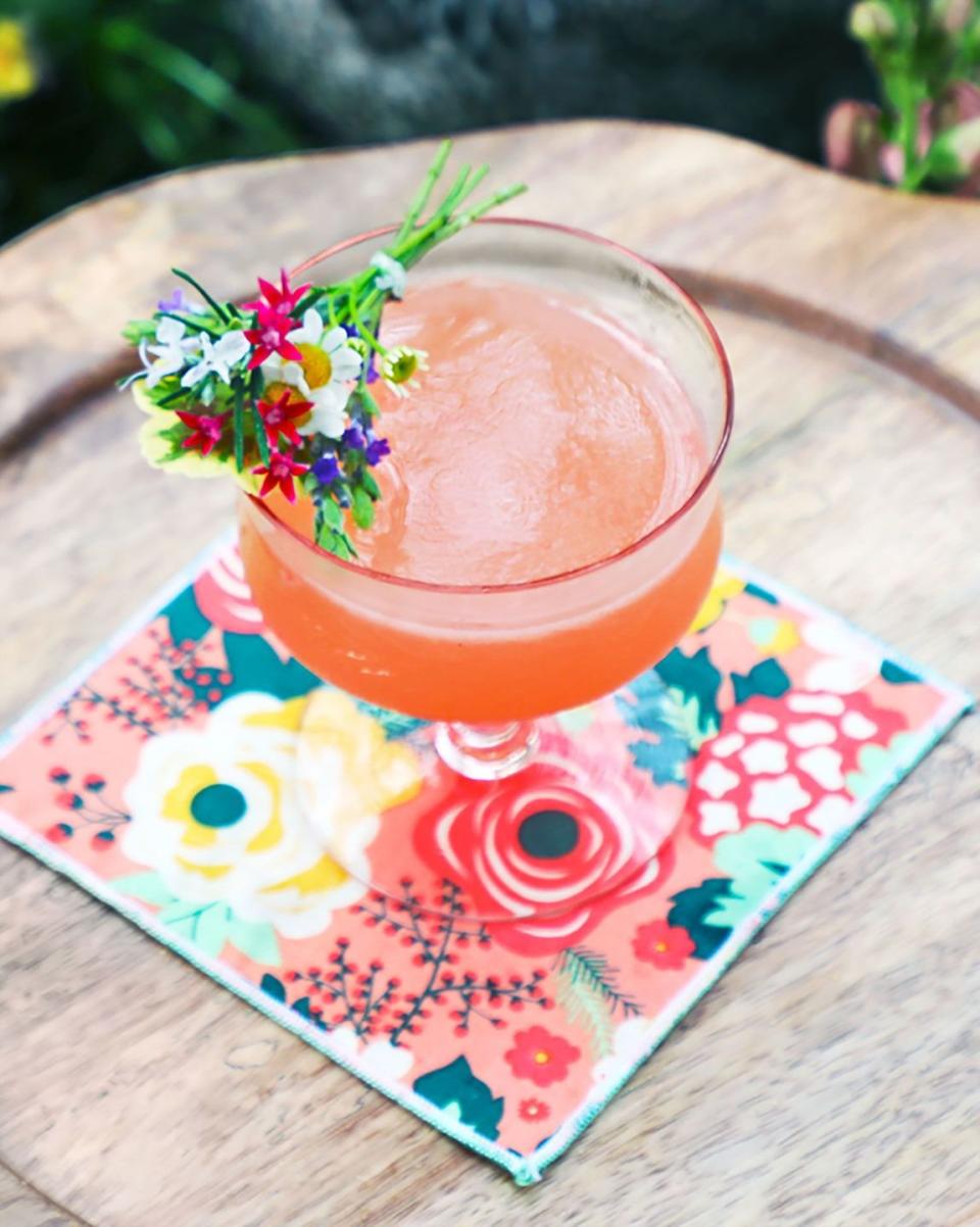 pink spring bouquet cocktail in a glass with a mini bouquet of small flowers perched on the rim