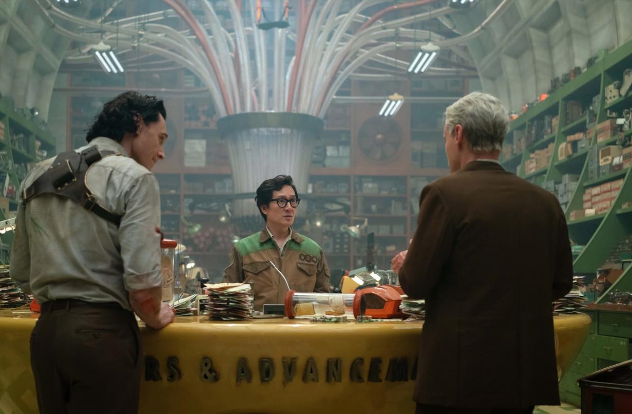  three men in a room packed with pneumatic tubes and assorted junk 