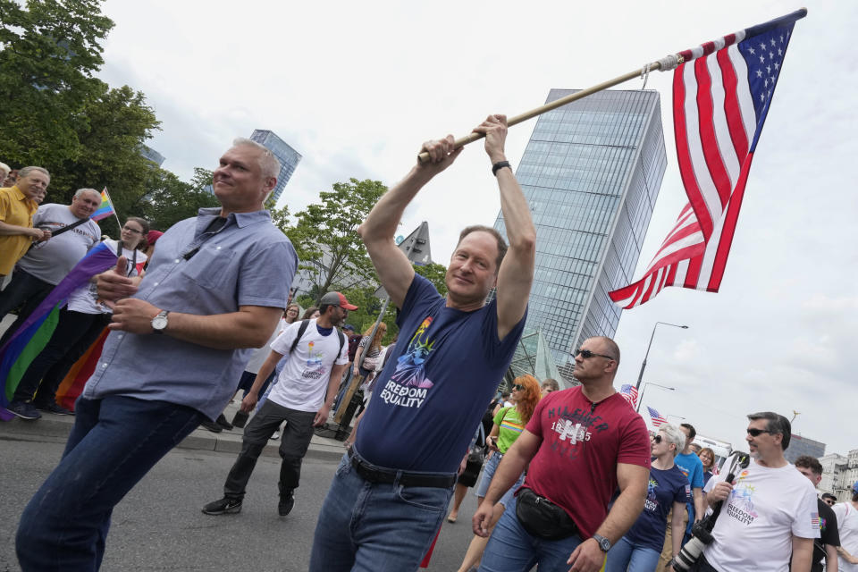 U.S. Ambassador Mark Brzezinski holds a U.S. flag as he marches in the yearly pride parade in Warsaw, Poland, on Saturday, June 17, 2023. The ambassador was sending a clear message of Washington's opposition to discrimination in a country where LGBTQ+ people are facing an uphill struggle. (AP Photo/Czarek Sokolowski)