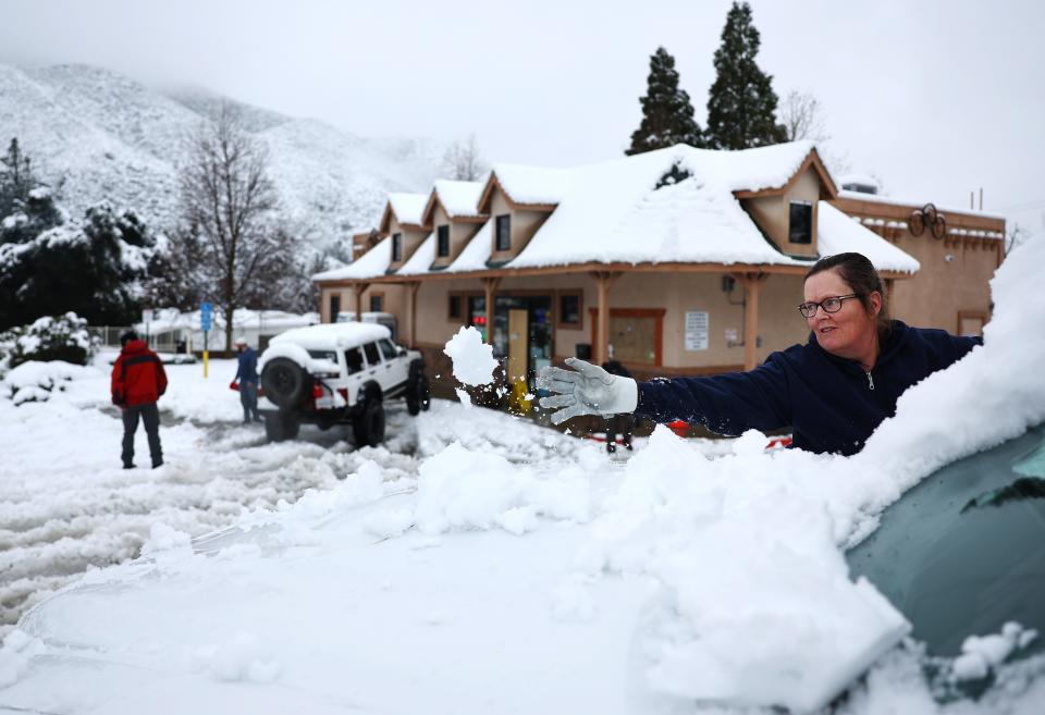 A person clears snow from their windshield in Los Angeles County, in the Sierra Pelona Mountains, on February 25, 2023 in Green Valley, California.