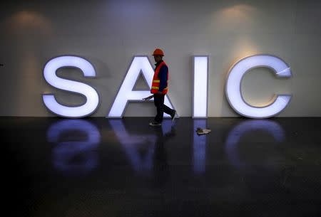 A worker walks past a lighted signage of the Shanghai Automotive Industry Corporation (SAIC) before the opening of the 15th Shanghai International Automobile Industry Exhibition in Shanghai in this April 19, 2013 file photo. REUTERS/Carlos Barria/File Photo