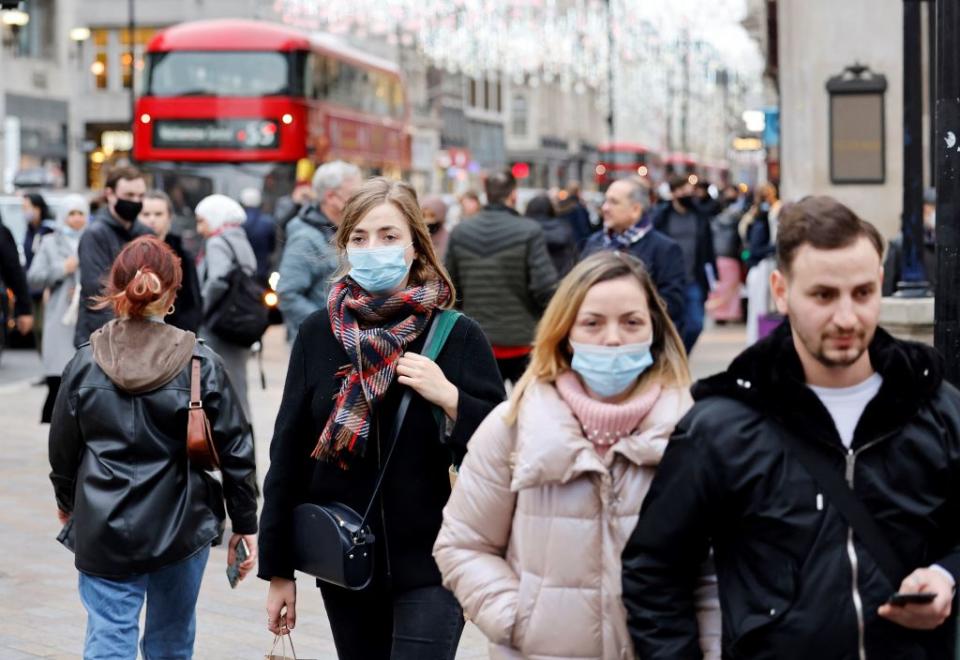 Pedestrians wearing face coverings to combat the spread of Covid-19, carry shopping bags as they walk past stores on Oxford Street in central London.