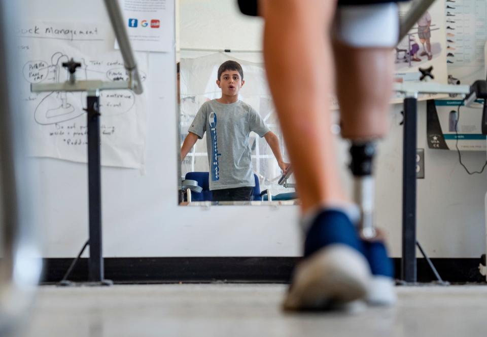 Saleh Humaid, 8, of Gaza, looks in a mirror while using rails to help as he tries walking for the first time on a new prosthetic leg at Anew Life Prosthetics and Orthotics in Detroit on Thursday, July, 27. 2023. Humaid’s leg was bombarded with the shrapnel from an exploding car he and his dad happened to be passing in the road as it was targeted for a drone strike. The damage to his nerves was too severe to repair and surgeons in the Gaza Strip could not save his limb.