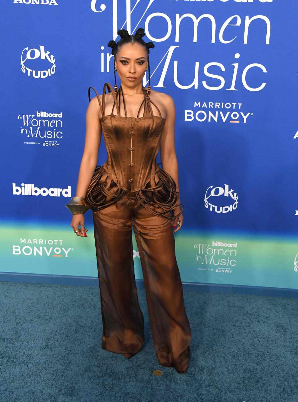 Kat in a unique strap-detailed corset top and matching pants poses with her hair in bantu knots