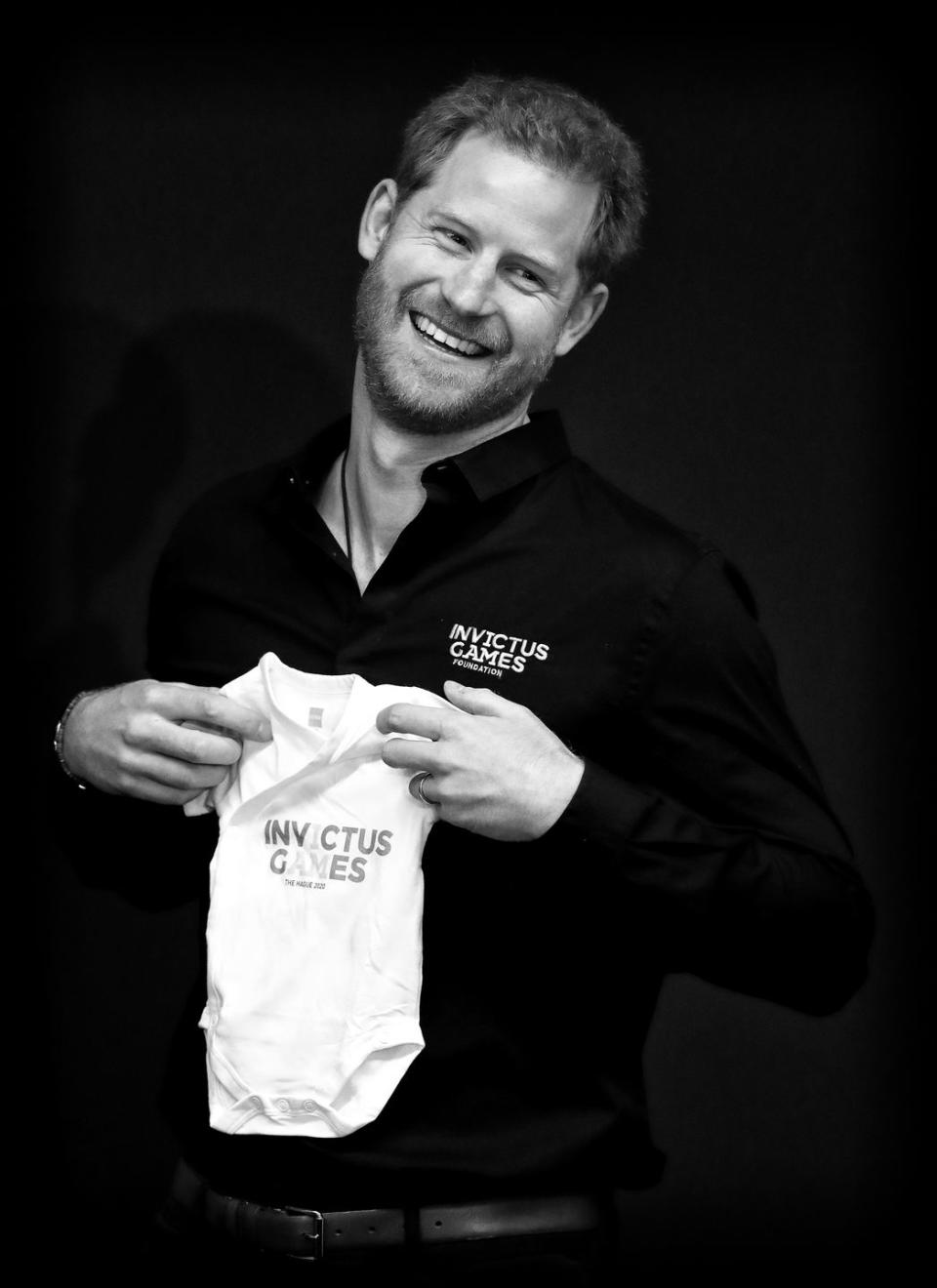 <p>Just days after Archie was born, Prince Harry traveled to the Netherlands <a href="https://www.townandcountrymag.com/society/tradition/g27418477/prince-harry-netherlands-invictus-games-2020-kickoff-photos/" rel="nofollow noopener" target="_blank" data-ylk="slk:to officially launch the 2020 Invictus Games;elm:context_link;itc:0;sec:content-canvas" class="link ">to officially launch the 2020 Invictus Games</a>. Here he is after receiving a sweet onesie for his new baby boy. </p>