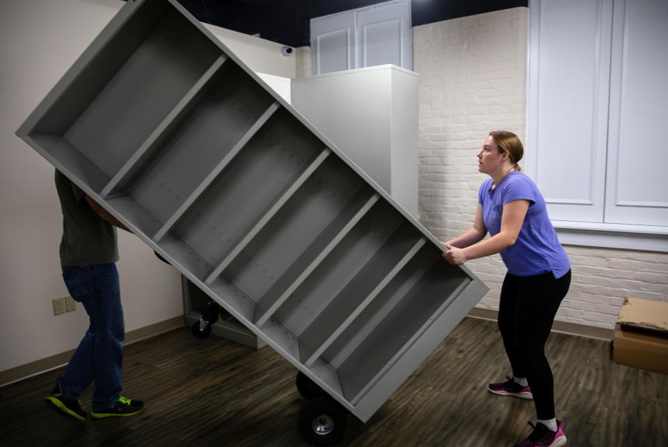 Hayley Jansen, right, helps Tom Deja move in cabinets that will house medication at Faith Community Pharmacy in Newport on June 1. The pharmacy's move from Florence is to accommodate a growing need for free prescription medications in Northern Kentucky.