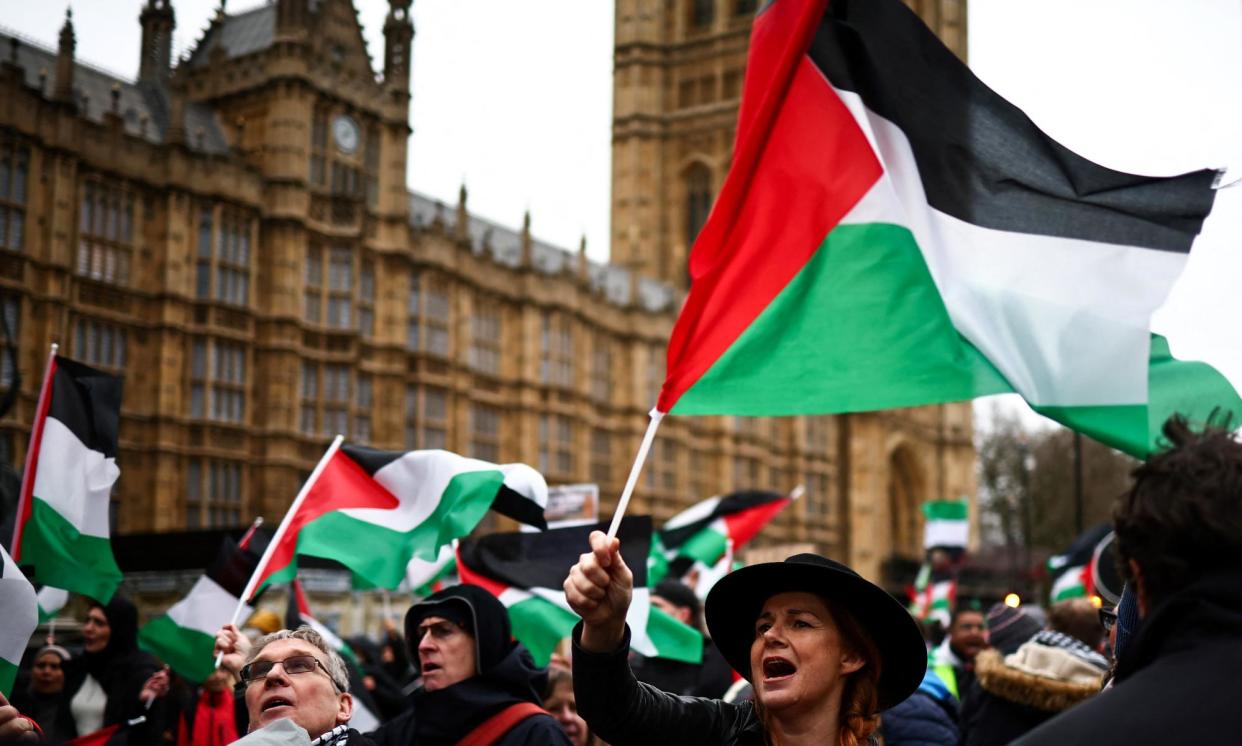 <span>Demonstrators wave Palestinian flags as they protest in Parliament Square, London on 21 February.</span><span>Photograph: Henry Nicholls/AFP/Getty Images</span>