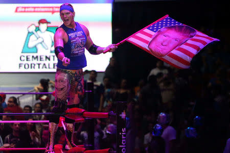 U.S. wrestler Sam Adonis, 27, role-playing as a fan of U.S. President Donald Trump, waves a flag with Trump's face during a wrestling fight at the Coliseo Arena in Mexico City, Mexico, February 12, 2017. Picture taken, February 12, 2017. REUTERS/Edgard Garrido