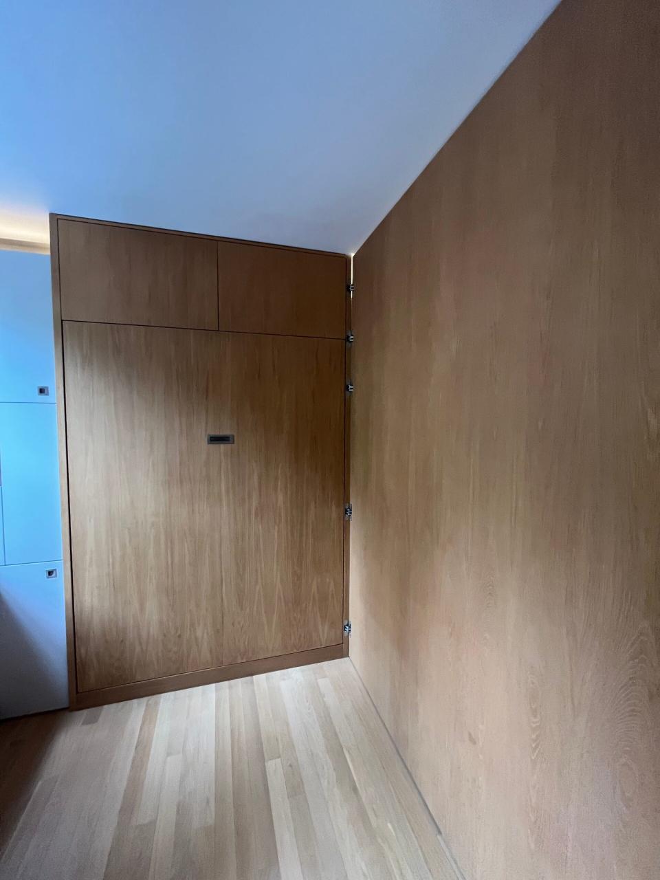 Inside the concealed bedroom with blonde wood walls 