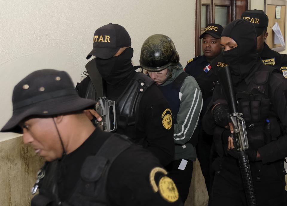 Rapper Daniel Hernandez, known as Tekashi 6ix9ine, is escorted by police to a different area of the court, the Palace of Justice, in Santo Domingo, Dominican Republic, Thursday, Jan. 25, 2024. Authorities arrested the rapper on Jan. 17 on charges of domestic violence. (AP Photo/Ricardo Hernandez)