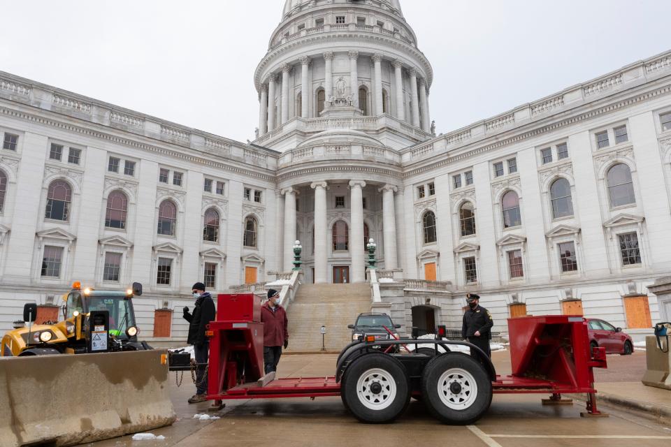 Under the supervision of a Capitol Police sergeant, workers set up a vehicle barricade on the E. Washington Ave.side of the Capitol January 15, 2021 in Madison. The FBI has received information on groups planning to storm government offices in every state the day President-Elect Joe Biden will be inaugurated, regardless of whether the state certified electoral votes for Biden or President Trump.