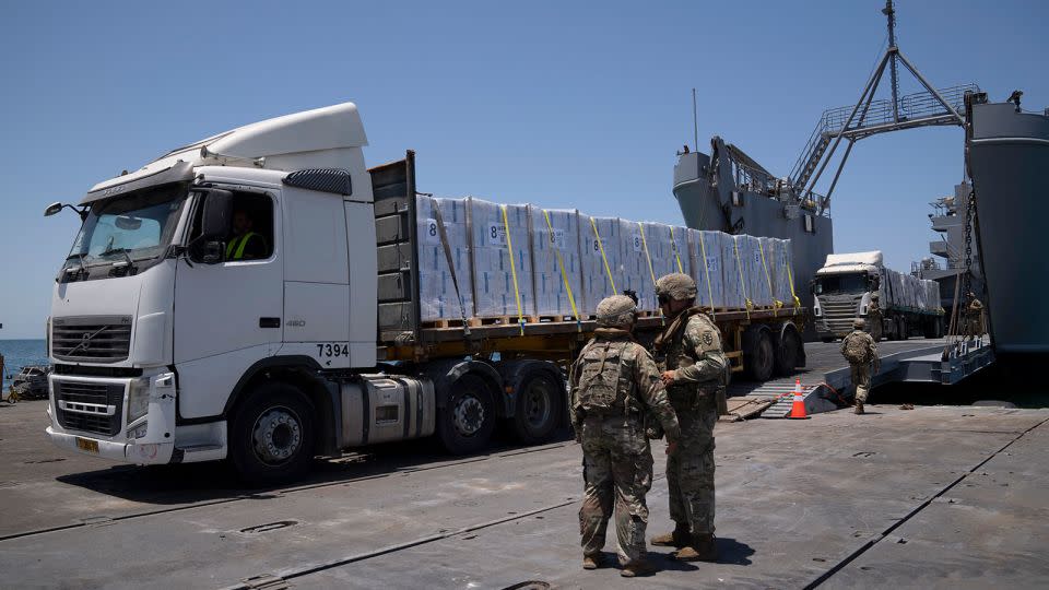 US Army soldiers stand next to trucks arriving loaded with humanitarian aid at the US-built floating pier Trident before reaching the beach on the coast of the Gaza Strip on June 25, 2024. - Leo Correa/AP