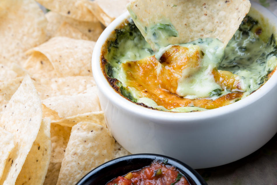 Tortilla chip dipping into Cheesy Spinach Dip