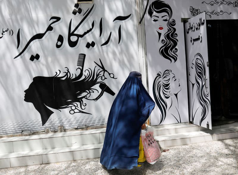 FILE PHOTO: An Afghan woman walks past a beauty salon in Kabul
