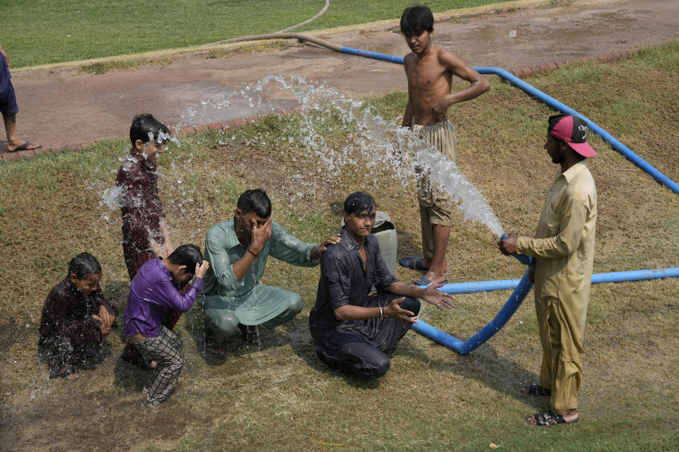 A worker sprays water to cool off youth at a park during a hot summer day in Lahore, Pakistan, Thursday, May 23, 2024. Doctors treated hundreds of victims of heatstroke at hospitals across Pakistan on Thursday after an intense heat wave sent temperatures above normal levels due to climate change, officials said. (AP Photo/K.M. Chaudhry)