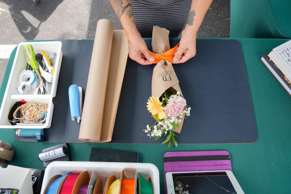 Jun 26, 2022; Columbus, Ohio, USA;  Annette Vasquez wraps a flower bouquet from her shop, Flowerday-ze, during the pop-up market, Mercadito Cositas Lindas, which helps small Latine-owned businesses, in the parking lot of Stewart Elementary in German Village on June 26, 2022. Mandatory Credit: Adam Cairns-The Columbus Dispatch
