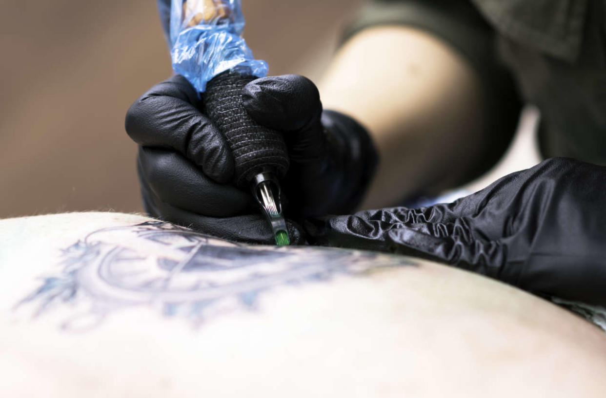 Close up tattooing process, Woman master getting tattoo in studio