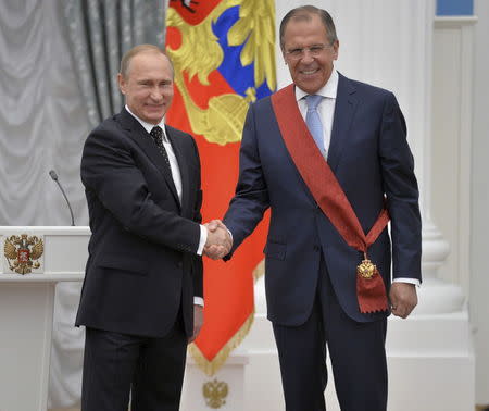 Russian President Vladimir Putin (L) shakes hands with Russian Foreign Minister Sergei Lavrov during an awarding ceremony at the Kremlin in Moscow, Russia, May 21, 2015. REUTERS/Alexei Druzhinin/RIA Novosti/Kremlin