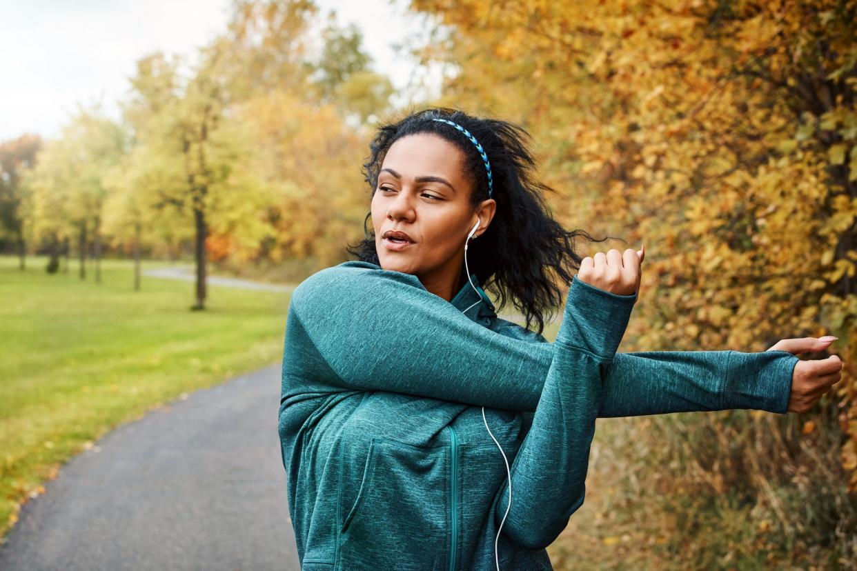 woman stretching on fall road before continuing workout