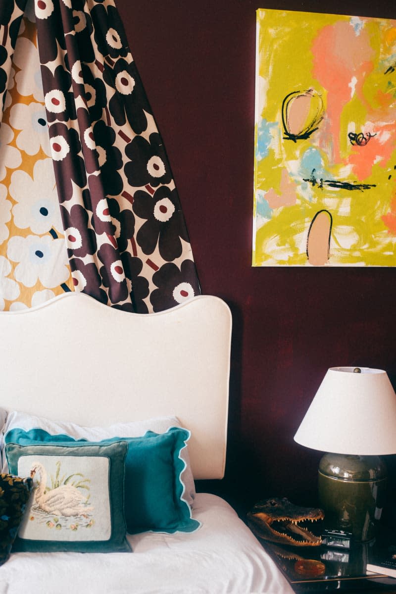 Floral Marimekko fabric hangs above white bed in dark purple bedroom.