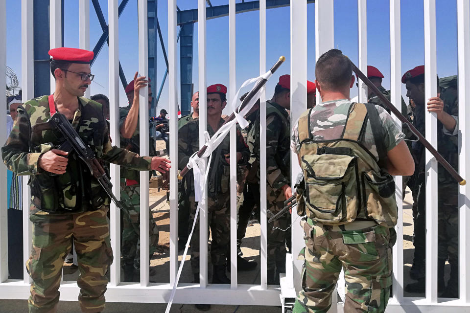 Iraqi and Syrian border guards prepare to open the crossing between the Iraqi town of Qaim and Syria's Boukamal in Anbar province, Iraq, Monday, Sept. 30, 2019. Iraq and Syria have opened a key border crossing between the two neighboring countries seven years after it was closed during Syria's civil war. (AP Photo/Hadi Mizban)