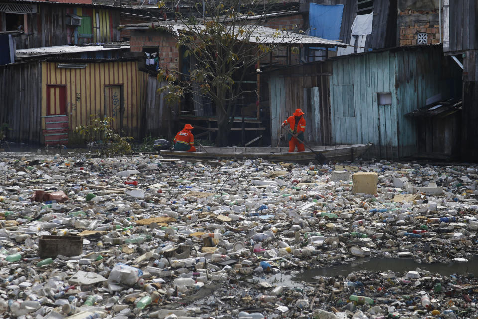 FILE - City workers remove garbage floating on the Negro River, which has a rising water level due to rain, in Manaus, Amazonas state, Brazil, June 6, 2022. The two-day Amazon Summit opens Tuesday, Aug. 8, 2023, in Belem, where Brazil hosts policymakers and others to discuss how to tackle the immense challenges of protecting the Amazon and stemming the worst of climate change. (AP Photo/Edmar Barros, File)