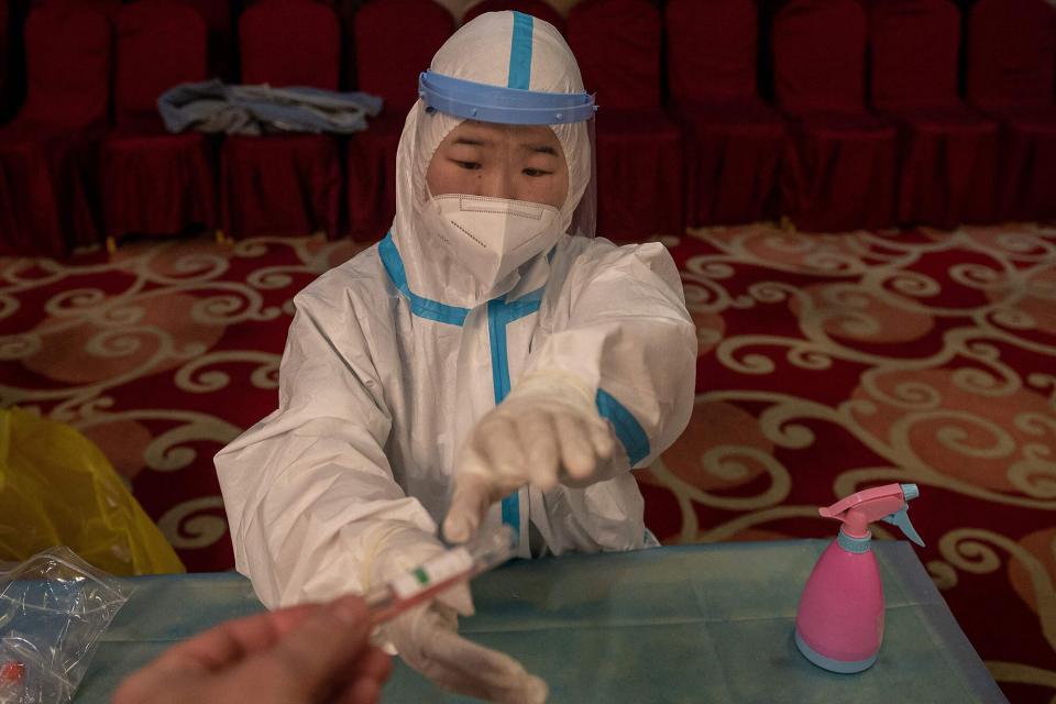 Un trabajador de la salud recibe un tubo de muestra para una prueba de ácido nucleico Covid-19, nueve horas antes de una conferencia de prensa de la cuarta sesión de la 13a. Conferencia Consultiva Política del Pueblo Chino (CPPCC) en el Hotel Internacional Huabin en Beijing