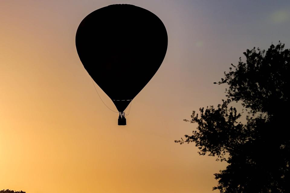 A hot-air balloon floats in silhouette across the sky Thursday, Aug. 11, 2022, during the FireLake Fireflight Balloon Fest in Shawnee.