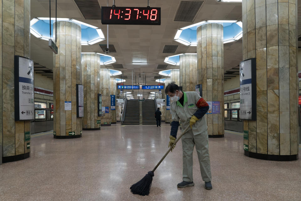 A worker cleans the floor of an empty subway station in Beijing, China. 