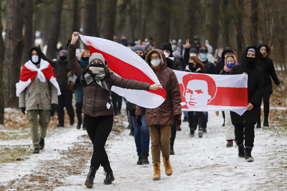 Demonstrators wearing face masks to help curb the spread of the coronavirus carry old Belarusian national flags during an opposition rally to protest the official presidential election results in Minsk, Belarus, Sunday, Dec. 13, 2020. Protests in Belarus have continued for almost four months after President Alexander Lukashenko won his sixth term in office in an election the opposition says was rigged. (AP Photo)