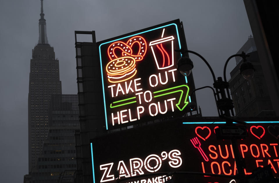 A billboard in midtown Manhattan reads "Take Out To Help Out, Monday, Nov. 30, 2020 in New York. (AP Photo/Mark Lennihan)