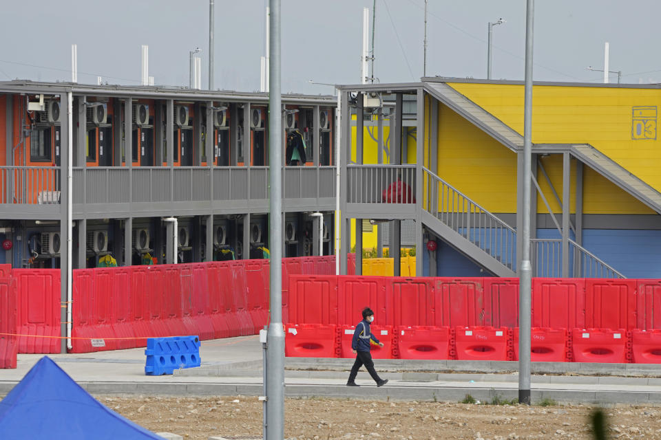 FILE - A worker walks at the isolation units in the Penny's Bay Quarantine Centre on Lantau Island, in Hong Kong on Feb. 24, 2022. The fast-spreading omicron variant is overwhelming Hong Kong, prompting mass testing, quarantines, supermarket panic-buying and a shortage of hospital beds. Even the morgues are overflowing, forcing authorities to store bodies in refrigerated shipping containers. (AP Photo/Kin Cheung, File)