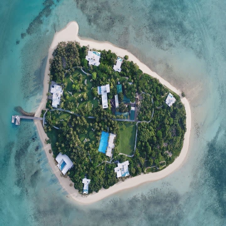 aerial view of the private island with eight villas and a main building. Each villa has a private pool and private beach access.