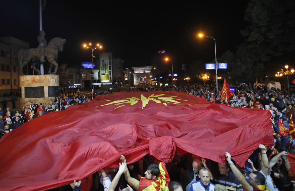 Supporters of a movement for voters to boycott the referendum, hold a huge Macedonian flag as they celebrate in central Skopje, Macedonia, after election officials gave low turnout figures, late Sunday, Sept. 30, 2018. The crucial referendum on accepting a deal with Greece to change the country's name to North Macedonia to pave the way for NATO membership attracted tepid voter participation Sunday, a blow to Prime Minister Zoran Zaev's hopes for a strong message of support. (AP Photo/Thanassis Stavrakis)