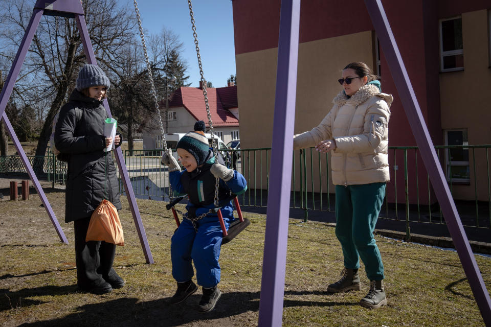 Olga Martynova, a la derecha, empuja a su hijo Alosha en un columpio mientras su hija Alysa observa, en el parque de su nueva escuela en Bialki Gorne, Polonia, el sábado 12 de marzo de 2022. (Erin Schaff/The New York Times)
