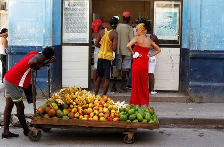 A man pushes a cart with fruits in front of a shop, as a picture of the former Cuban President Raul Castro is seen on the wall, in Havana, Cuba July 21, 2018. REUTERS/ Stringer