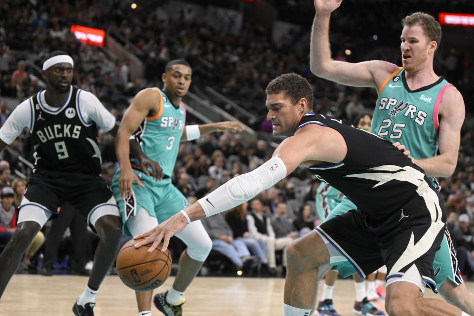 Milwaukee Bucks' Brook Lopez grabs the ball ahead of San Antonio Spurs' Jakob Poeltl (25) as Spurs' Keldon Johnson (3) and Bucks' Bobby Portis Jr. (9) watch during the second half of an NBA basketball game, Friday, Nov. 11, 2022, in San Antonio. (AP Photo/Darren Abate)