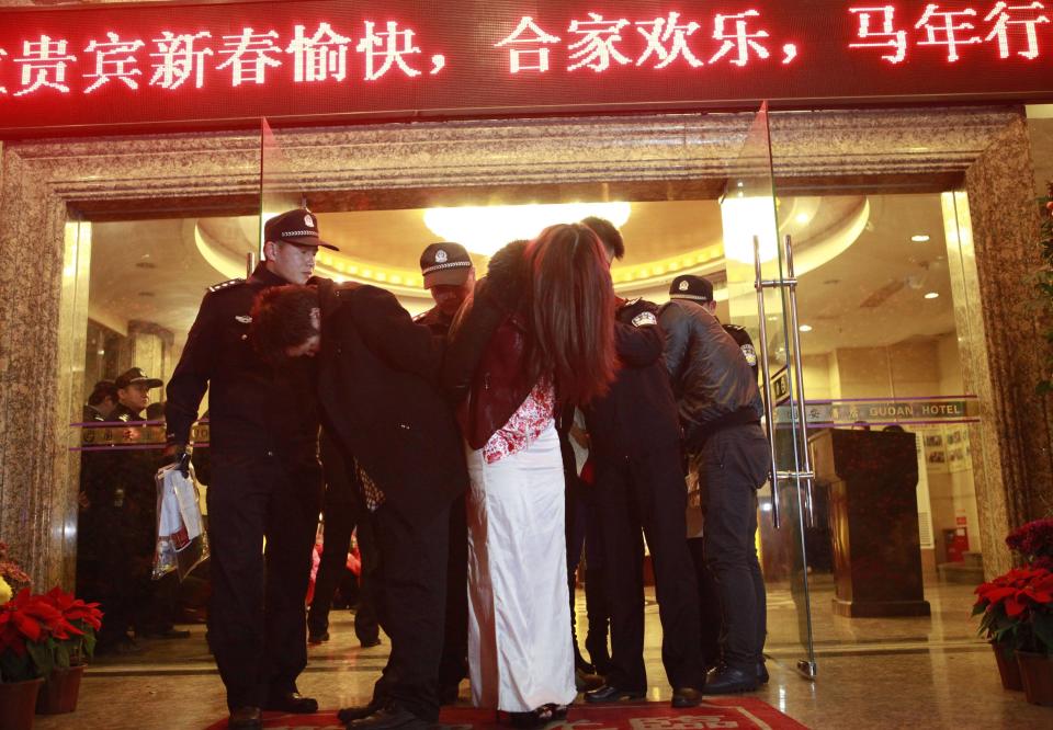 People are taken away during a police raid, as part of plans to crackdown on prostitution, from a hotel in Dongguan, Guangdong province, February 9, 2014. Chinese authorities have carried out a rare crackdown on the sex trade in the "sin city" of Dongguan following a candid report by the state broadcaster on the underground industry. Picture taken February 9, 2014. REUTERS/Stringer (CHINA - Tags: CRIME LAW TPX IMAGES OF THE DAY) CHINA OUT. NO COMMERCIAL OR EDITORIAL SALES IN CHINA