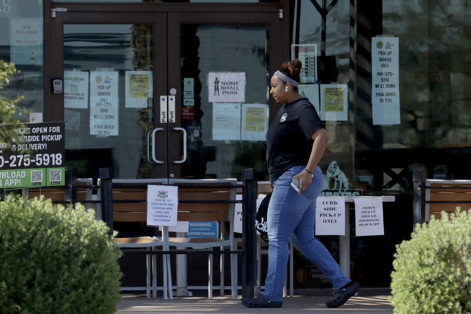 A person passes a temporary take-out only restaurant Friday, March 27, 2020, in Phoenix. Arizona is ramping up its unemployment insurance operations as it sees an unprecedented flood of new claims as the COVID-19 coronavirus staggers industries that are key to the state's economy. Arizona's food service industry employs about 230,000 people and an estimated 80% have been furloughed or laid off. (AP Photo/Matt York)