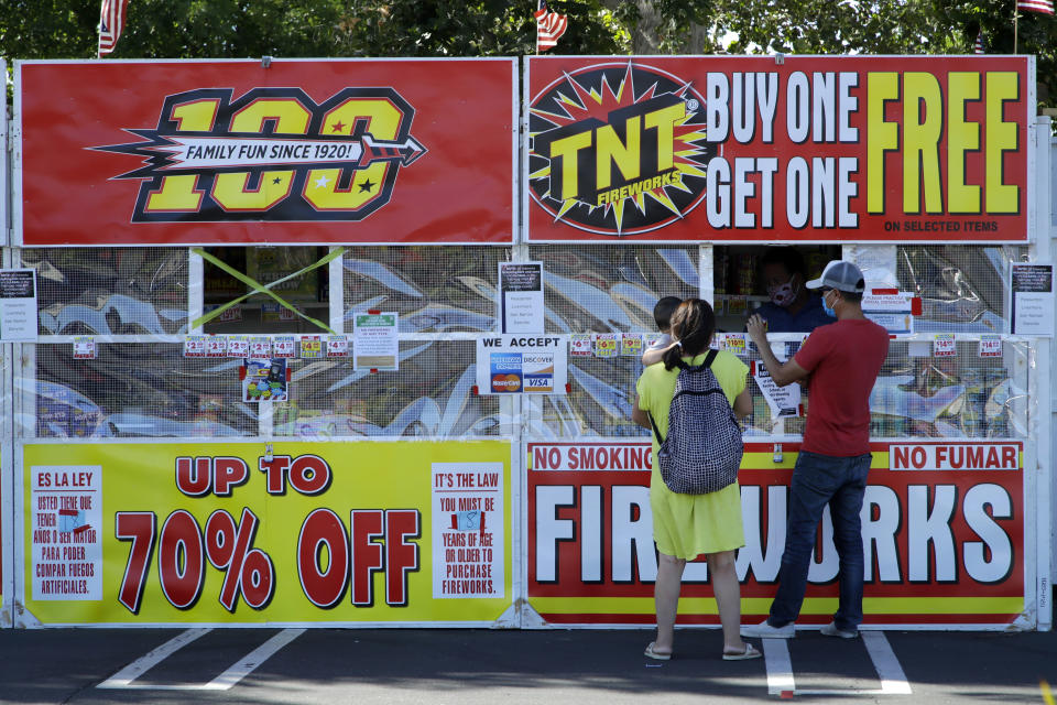 People purchase fireworks on Thursday, July 2, 2020, in Dublin, Calif. For many Americans, the Fourth of July won't be about big festivities but setting off fireworks themselves. Hundreds of cities and towns have canceled shows Saturday because of the coronavirus pandemic, and sales of consumer fireworks are booming; though officials are concerned about fires and injuries with more pyrotechnics going off in backyards and at block parties. (AP Photo/Ben Margot)