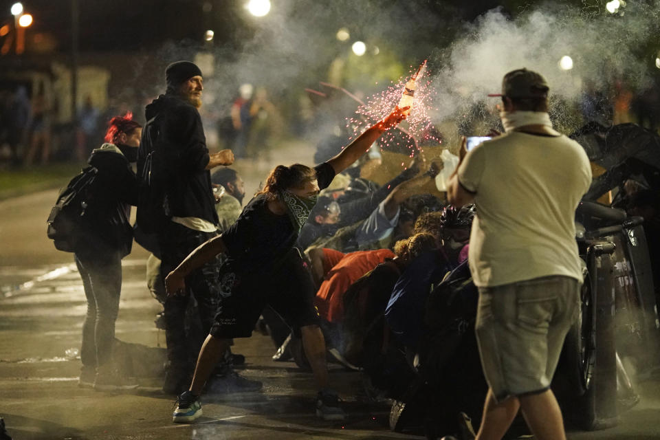 A protester tosses an object toward police during clashes outside the Kenosha County Courthouse late Tuesday, Aug. 25, 2020, in Kenosha, Wis., on third night of unrest following the shooting of a Black man, Jacob Blake, whose attorney said he was paralyzed after being shot multiple times by police. (AP Photo/David Goldman)