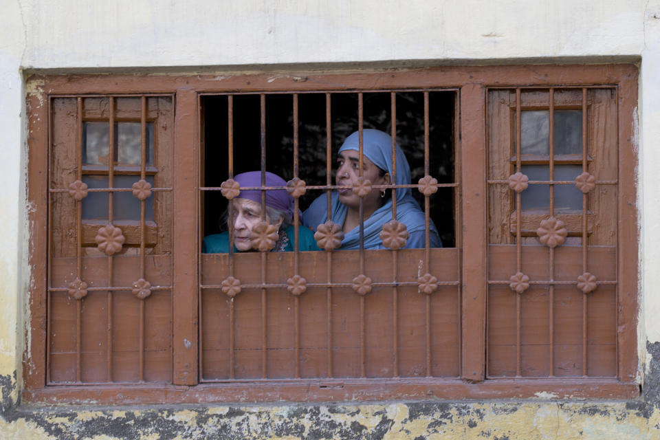 Kashmiri women look towards the site of a gunbattle from the window of their house in Srinagar, India, Wednesday, Oct. 17, 2018. Anti-India protests and clashes erupted in the main city of disputed Kashmir on Wednesday shortly after a gunbattle between militants and government forces killed at least two suspected rebels and a counterinsurgency police official. (AP Photo/Dar Yasin)