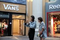 Young women are seen outside a Vans store at a shopping center in Beijing