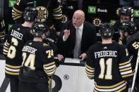 Boston Bruins head coach Jim Montgomery, center, talks with Jake DeBrusk (74), Mason Lohrei (6)and Trent Frederic (11) during a timeout in the third period of Game 3 of an NHL hockey Stanley Cup second-round playoff series against the Florida Panthers, Friday, May 10, 2024, in Boston. (AP Photo/Michael Dwyer)